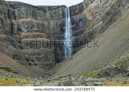 Hengifoss waterfall in Iceland. This waterfall is surrounded by basaltic strata layers and red layers of clay.