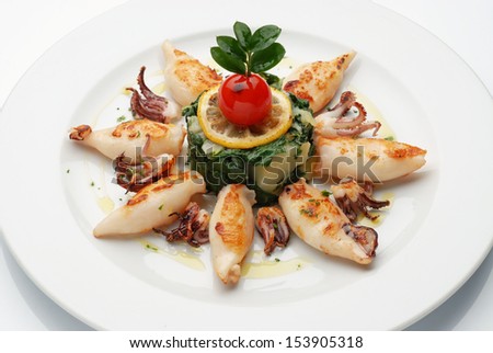 Grilled squid on plate with cooked potatoes and chard.