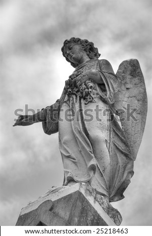 A statue of a mourning angel under moody skies atop a tomb in New Orleans.