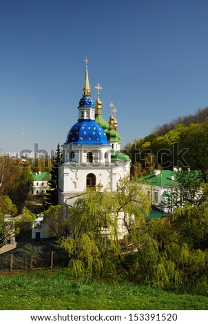 Orthodox church is sunlit in the middle of spring park. Beautiful edifice is buried in verdure.