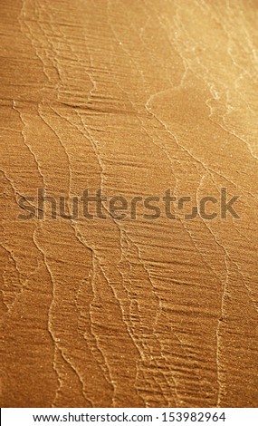 Wavy patterns of wet river sand on the beach. Gradient of sandy brown color.