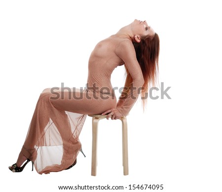 Slender girl sits on the chair with back arched, isolated on white.