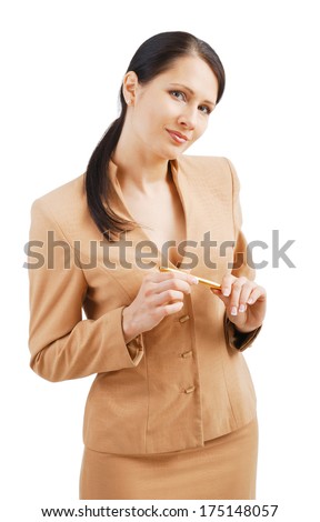 A pretty businesswoman is standing and holding a golden pen. The friendly woman is looking at the camera and smiling gently. She is wearing a lounge suit.