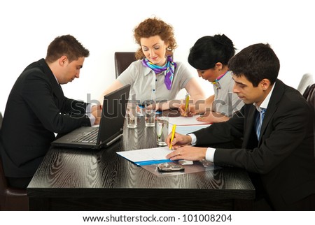 Busy business people in office sitting on chairs at meeting table and writing on papres