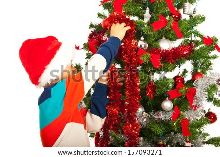 Schoolboy decorate Christmas tree  and wearing colorful clothes and Santa hat