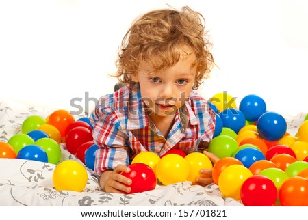 Thinking boy with colorful balls laying down