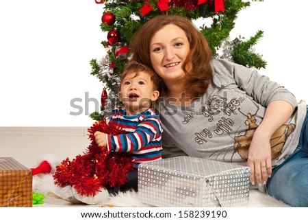 Happy mother and baby son under Christmas tree