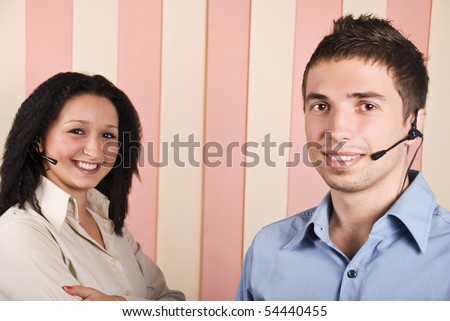 Young team with two people,woman and man customer service with headphone smiling and looking you,focus on man