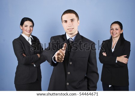 Three business people team with two women with arms folded and a business man in front of image giving thumbs up,concept of successful teamwork on blue background