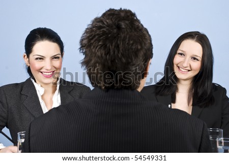 A business man back having a job interview with two business women and they laughing together