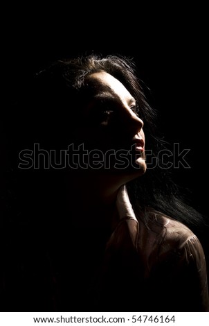 Portrait of beautiful brunette woman looking away in darkness  with soft light on her face