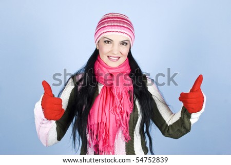 Successful happy winter woman giving thumbs up with gloves in hands and smiling for you in front of blue background