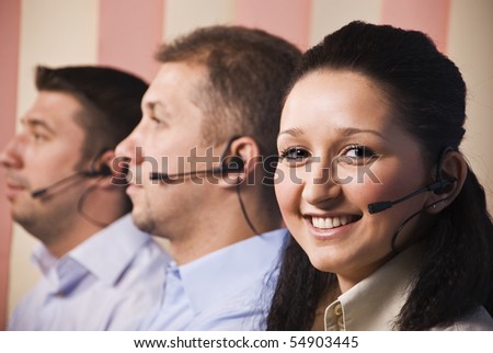 Three people sales representative working in office,focus on woman smiling,men standing in profile with headset