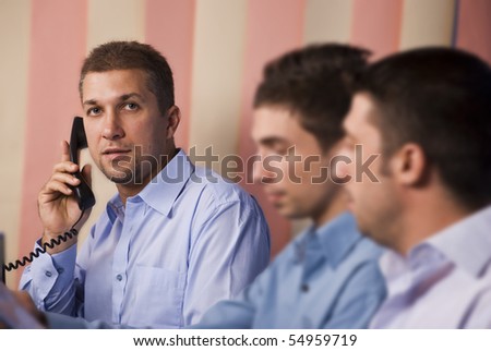 Three business men operators working in office,focus on last man having a conversation by telephone