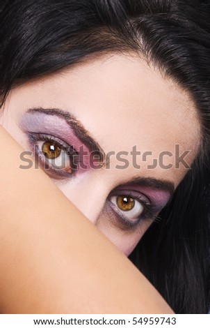 Brunette woman holding a hand and cover face but let seen only beautiful eyes with pink violet make up