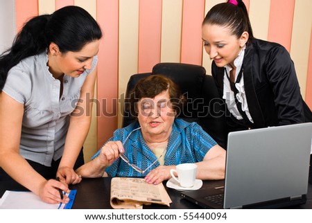 Senior manager business woman having a conversation with two young secretary and they all discussing about the news from a newspaper