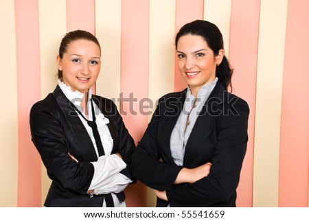Happy two young business women standing with arms folded and smiling in front of camera