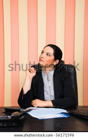 Thoughtful business woman  sitting on chair at desktop in office ,holding a pencil to chin and looking away