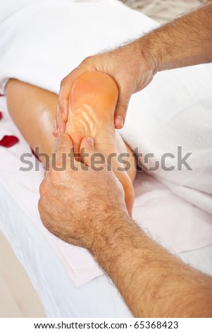 Masseur giving reflexology massage to woman feet