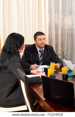 Two business people having discussion with others at meeting