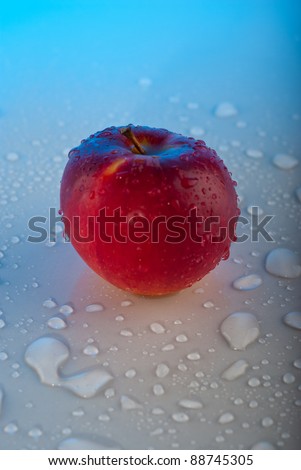 Red apple with water drops on gray table   with blue light