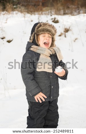 Toddler boy  screaming  because holding a snow ball in the hand for first time and it is too cold