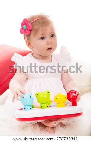 Attentive baby girl looking away and playing with toys