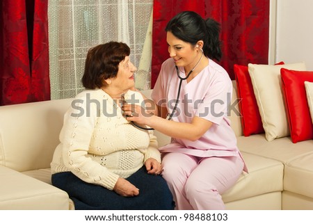 Doctor woman examine elderly patient in her home and sitting together on couch