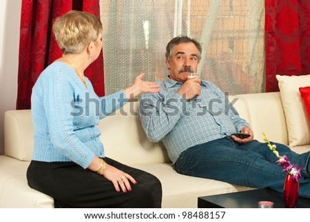 Mature couple having conflict in their house  and the man drinking beer and listening wife