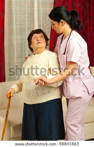 Nurse helping elderly woman to walk in her home
