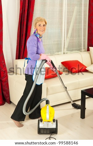 Senior housewife cleaning her  living room with vacuum cleaner