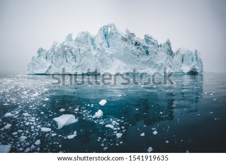 Arctic nature landscape with icebergs in Greenland icefjord with midnight sun sunset sunrise in the horizon. Early morning summer alpenglow during midnight season. Ilulissat, West Greenland.
