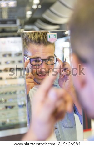 Man in optical center trying eyeglasses on
