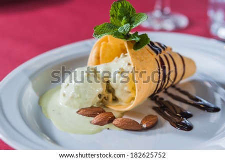 piece of ice cream with chocolate syrup, almonds and strawberry leaf