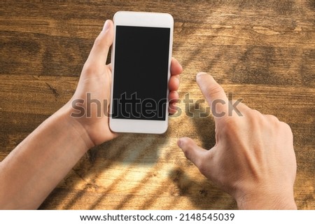 Human holding a smartphone on the screen. Rustic wooden table.tic wooden table. Rio de Janeiro, RJ, Brazil. January 2022. Foto stock © 