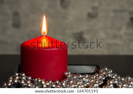 Red candle with a decor from silver balls
