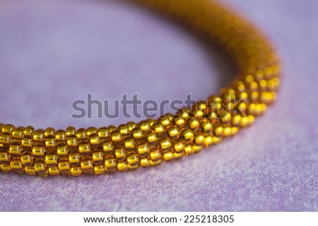 Fragment of a knitted yellow necklace from beads close up