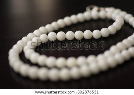 Necklace from stone white beads on a dark surface close up