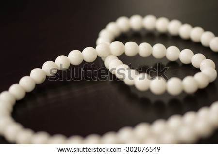 Necklace from stone white beads on a dark surface close up