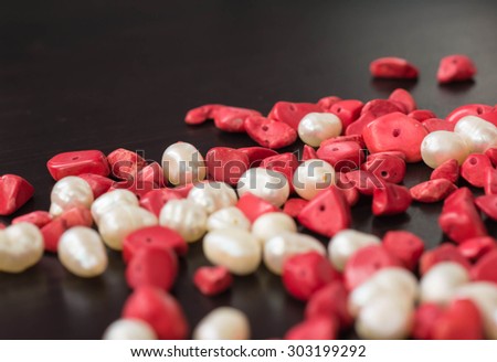 The scattered beads of red and white color on a dark wooden background