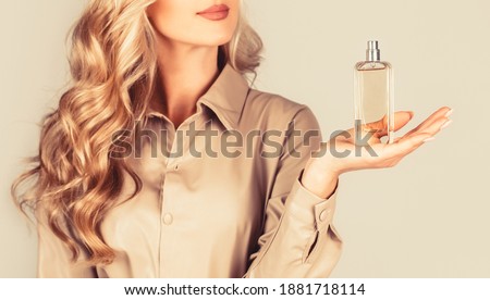 Beautiful girl using perfume. Woman with bottle of perfume. Woman presents perfumes fragrance. Perfume bottle woman spray aroma. Woman holding a perfumes bottle. Womans with perfum bottle.