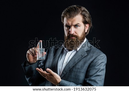 Perfume or cologne bottle and perfumery, cosmetics, scent cologne bottle, male holding cologne. Masculine perfume, bearded man in a suit. Male holding up bottle of perfume. Man perfume, fragrance.