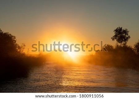 Sunset sky background. Gold sunset sky with evening sky clouds over the lake with fog.Crystal clear water texture. Small waves with water reflection