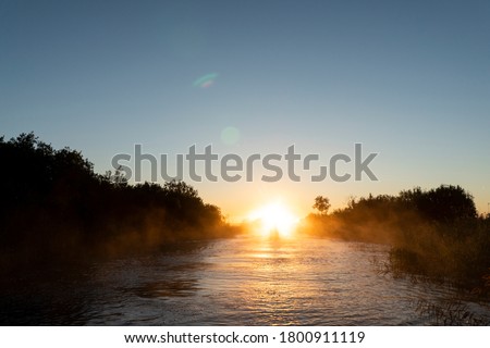 Sunrise sky background. Gold sunrise sky with sky clouds over the lake with fog.Crystal clear water texture. Small waves with water reflection