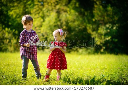 A little cute girl and a boy holding a plastic phrase 
