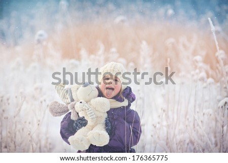 A cute smiling child in the warm clothing playing with her toy on a frosty winter day