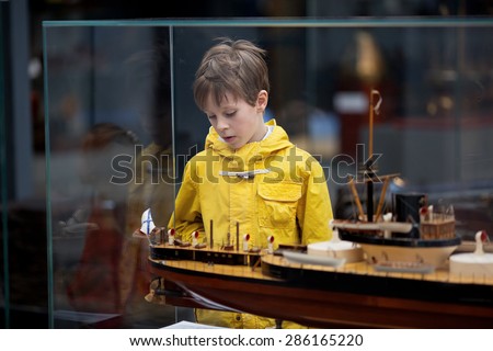 A young boy in a yellow raincoat examining ship models in The Naval Museum in Saint-Petersburg