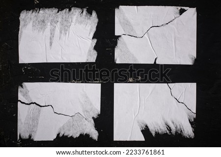 Four sheets of white torn paper on a black wall. Foto stock © 