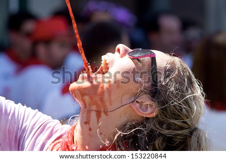 PAMPLONA, SPAIN - JULY 6: Woman drinking red wine at opening of San Fermin festival. Plaza Consistorial in front of municipality. Pamplona, Navarra, Spain July 6, 2013