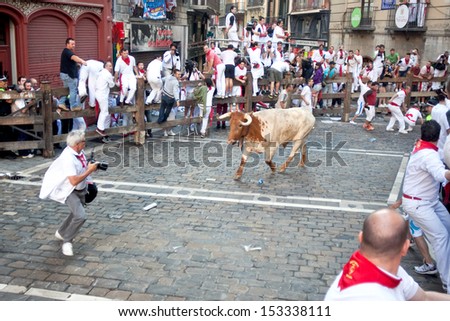 PAMPLONA, SPAIN - JULY 8: Bull runs at photographer at San Fermin festival. Pamplona, Navarra, Spain July 8, 2013.